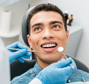 Man in denim shirt smiling at dentist about to examine his teeth