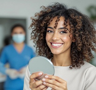 Woman smiling while holding small mirror