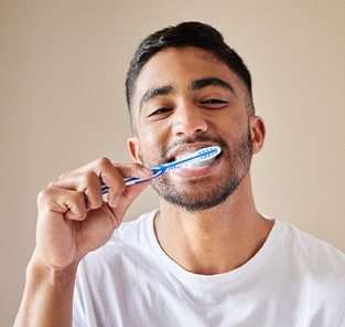 Man in white t-shirt brushing his teeth