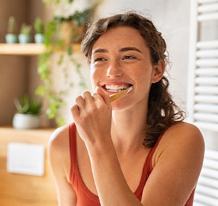Woman smiling while brushing her teeth