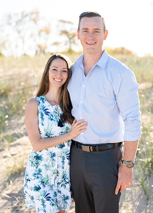 Doctors Eric and Ariel Heisser smiling by the beach