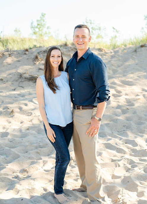 Doctors Eric and Ariel Heisser smiling by the beach