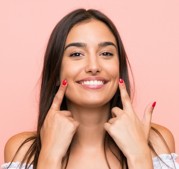 Woman pointing to smile after teeth whitening