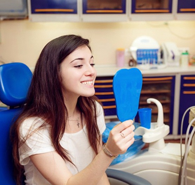 young woman seeing her new smile in a mirror