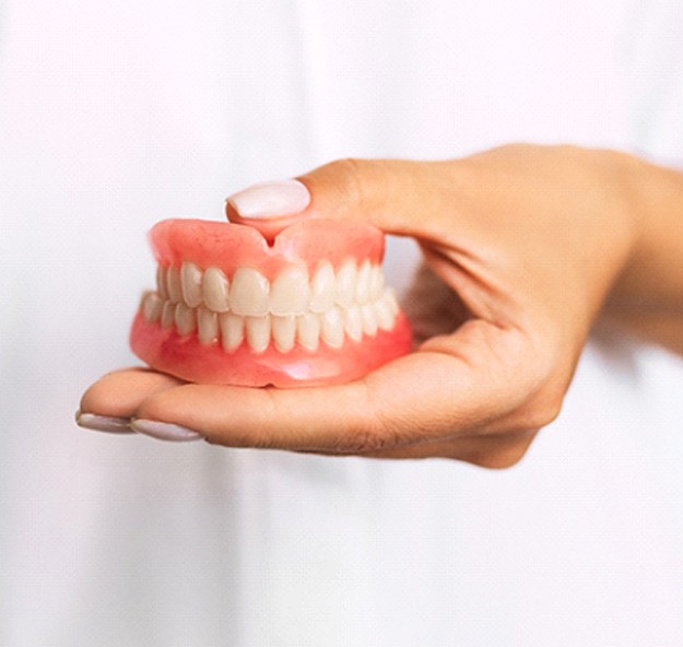 Dentist holding full dentures in Norton Shores