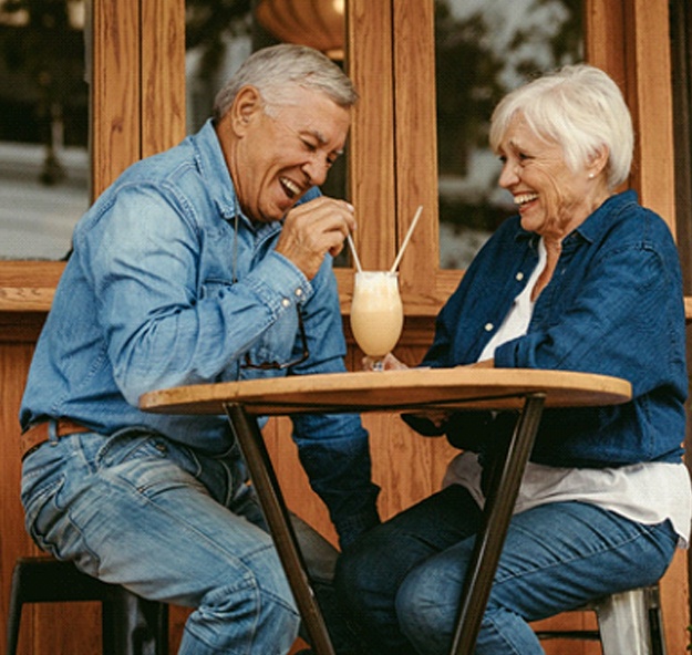 Senior couple with dentures in Norton Shores sharing a milkshake