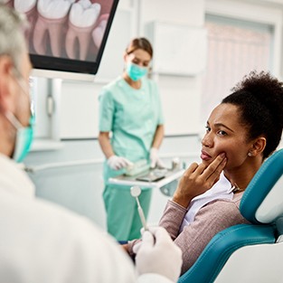 Patient with toothache looking at dentist in treatment chair