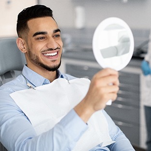 Patient smiling at reflection in handheld mirror