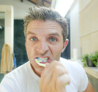 Man with dental implants in Norton Shores brushing his teeth