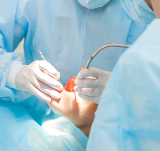 Dentists in blue scrubs working on patient’s mouth