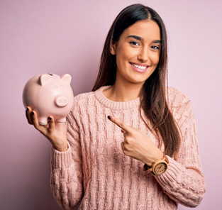 Woman in pink sweater pointing to pink piggy bank in her other hand