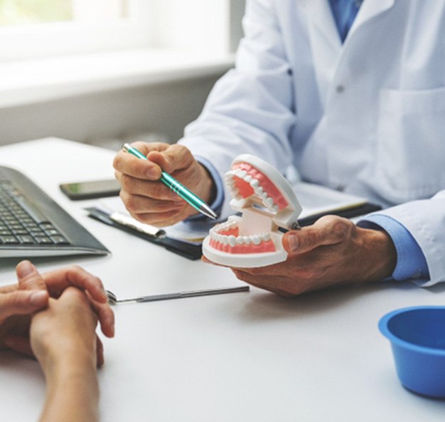 Patient and dentist sitting at desk, discussing dental implant treatment