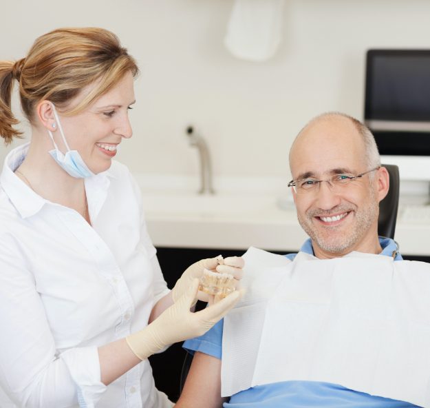 Denttist showing dental implant model to patient