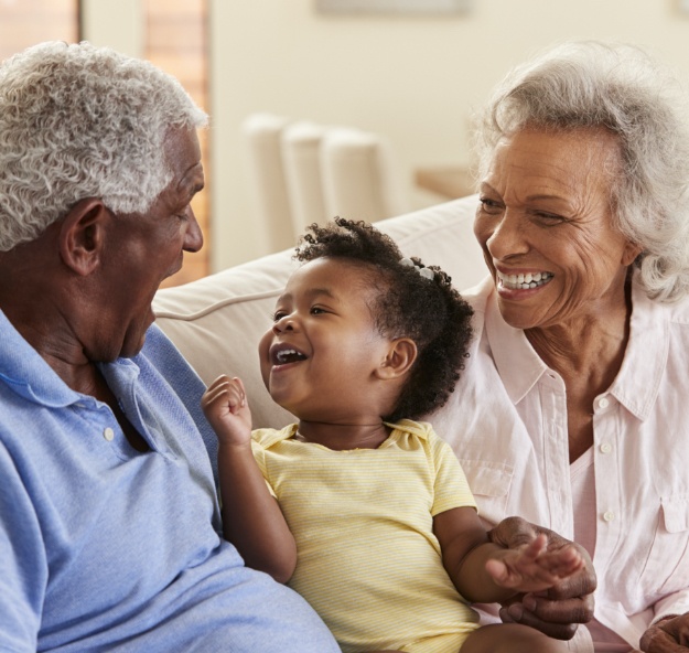 Grandparents smiling at grandchild after dental implant tooth replacement