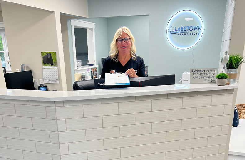 Two Norton Shores dental team members smiling behind front desk