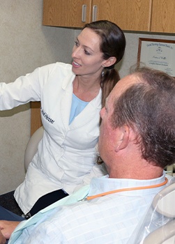 Woman smiling during treatment with dental team member and dentist