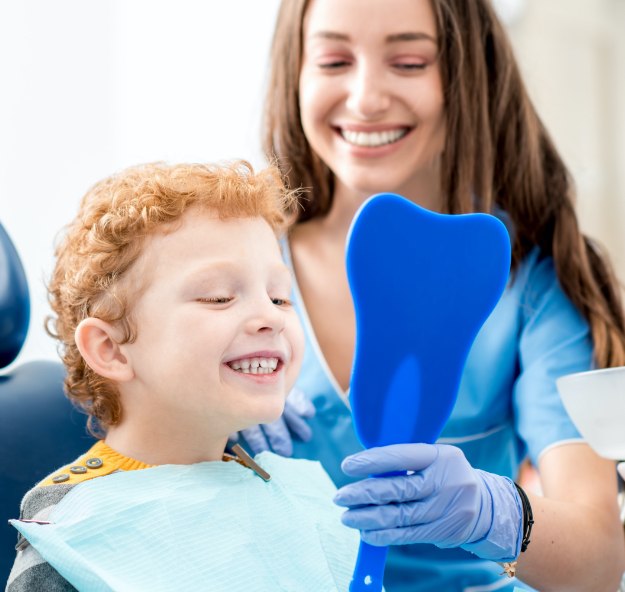 Young child looking at smile in mirror during children's dentistry treatment