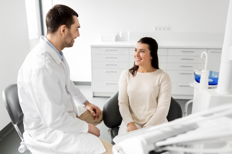 person sitting in dental chair speaking to dentist