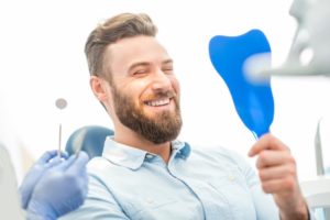 a man smiling in the mirror at his cosmetic dental treatment