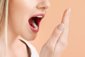 Woman using hand to check freshness of breath