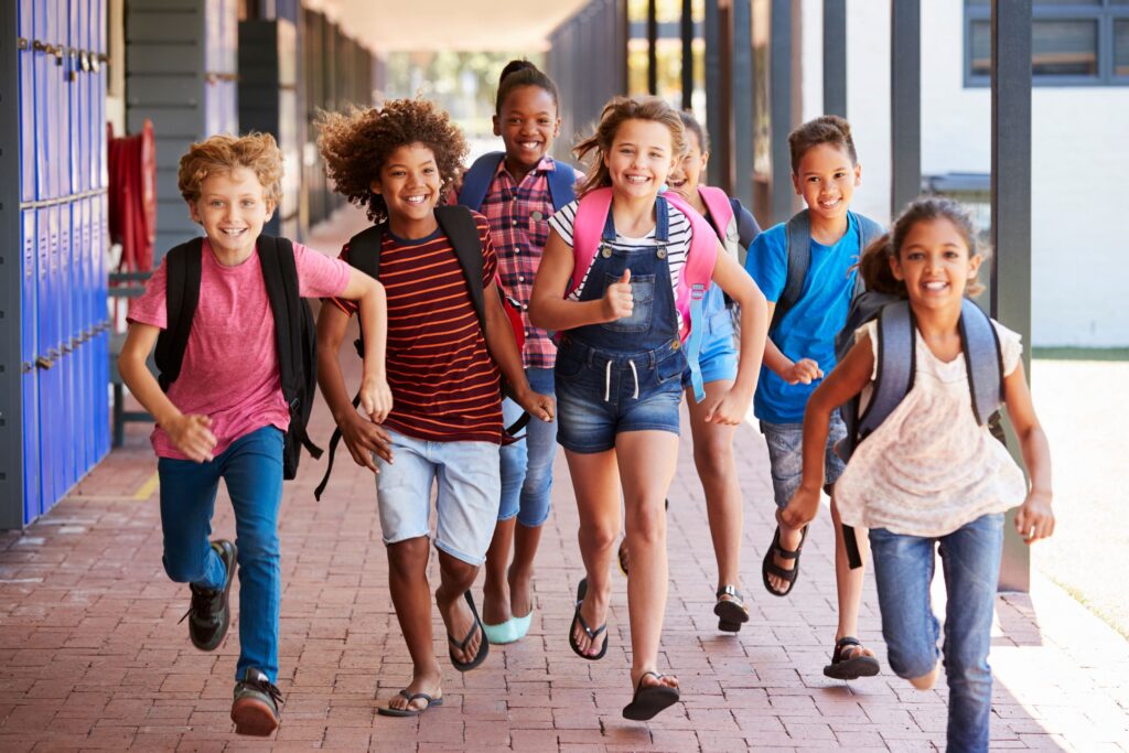 Group of kids with backpacks on running down school hallway